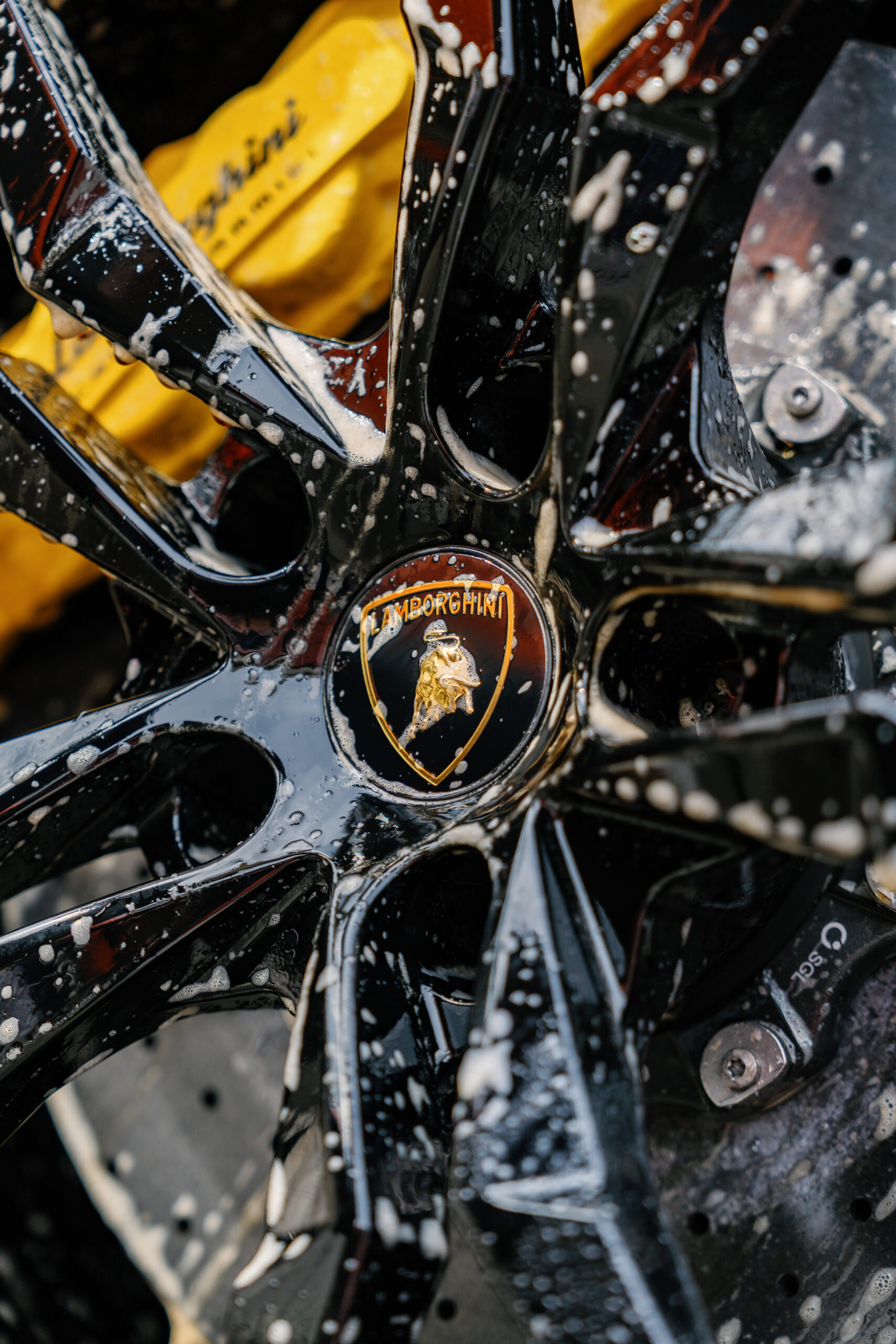 Close-up of a Lamborghini wheel covered in soap suds during a professional hand car wash by ATD Orlando.